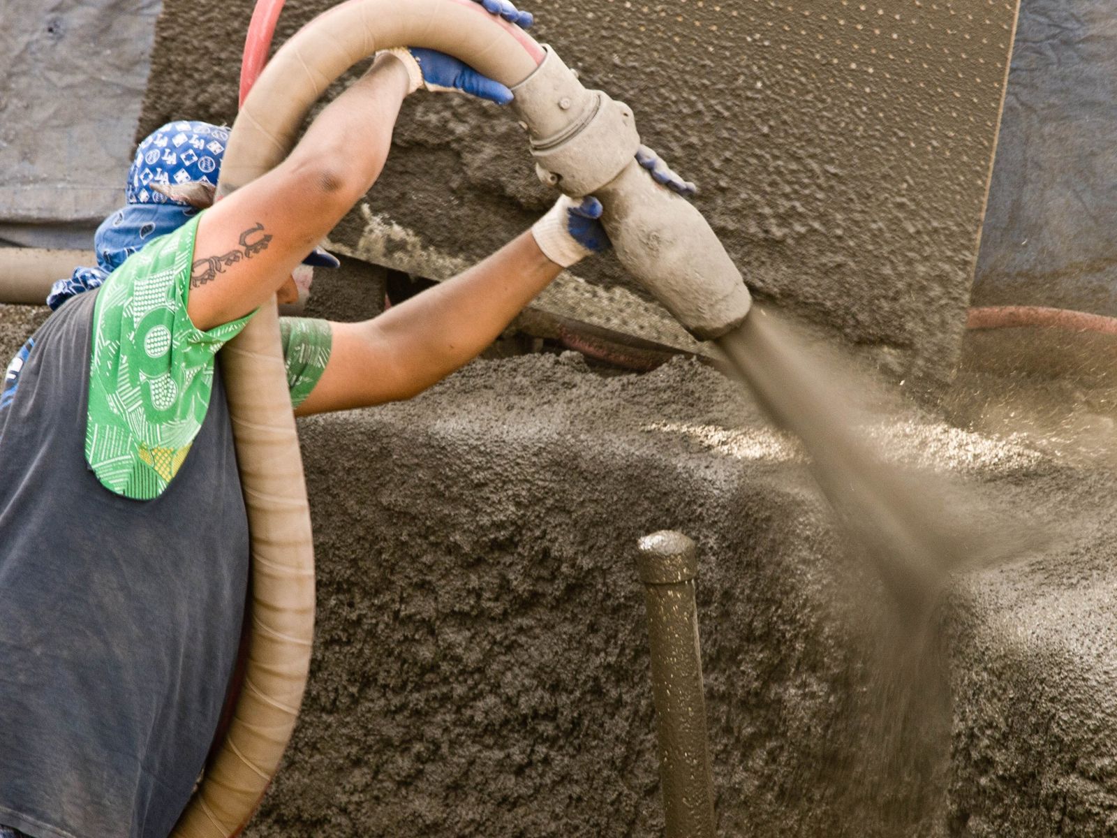 Arbeiter spritzt Beton auf die Schale eines Pools im Bau