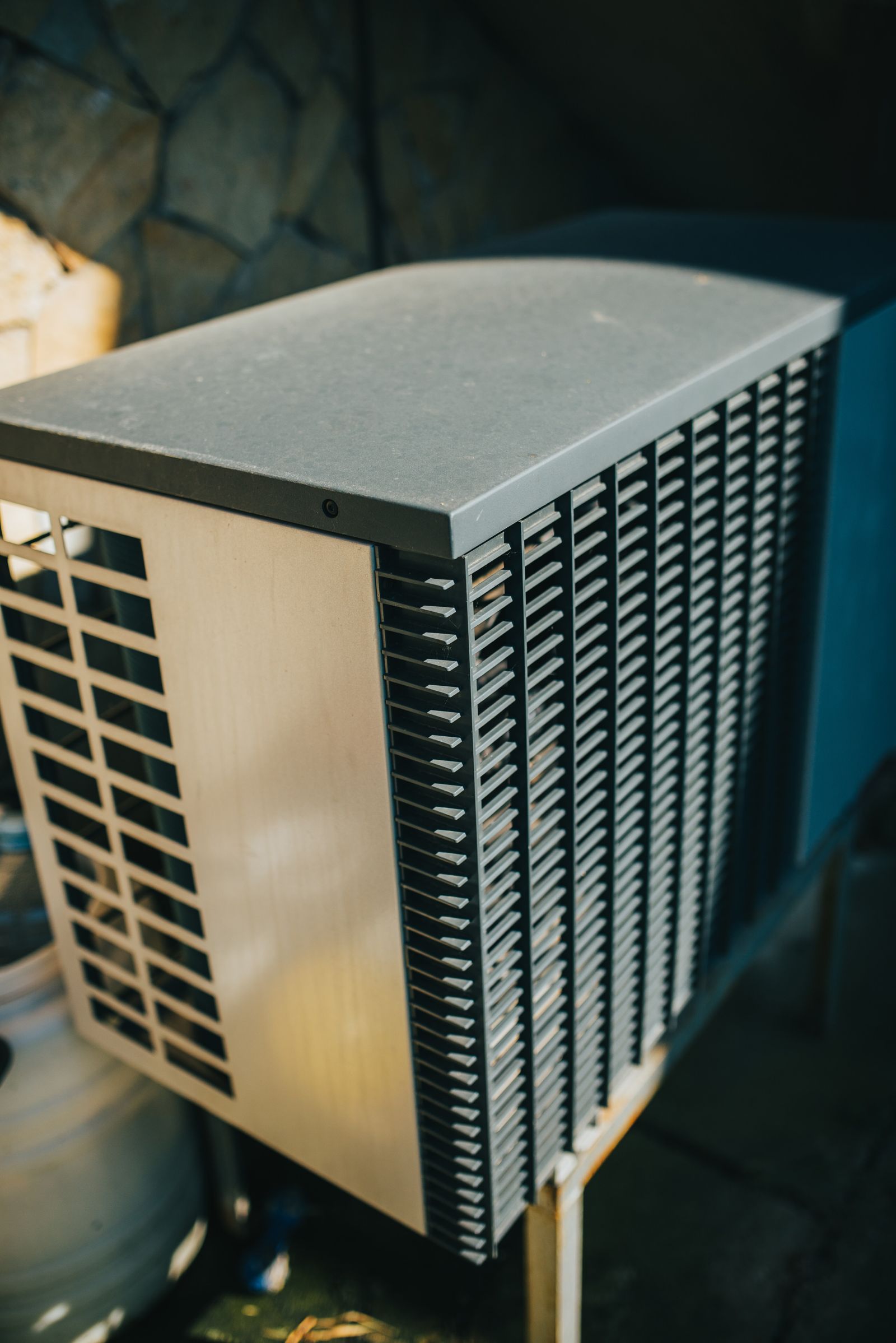 Outdoor air-conditioning unit mounted next to a house in a garden