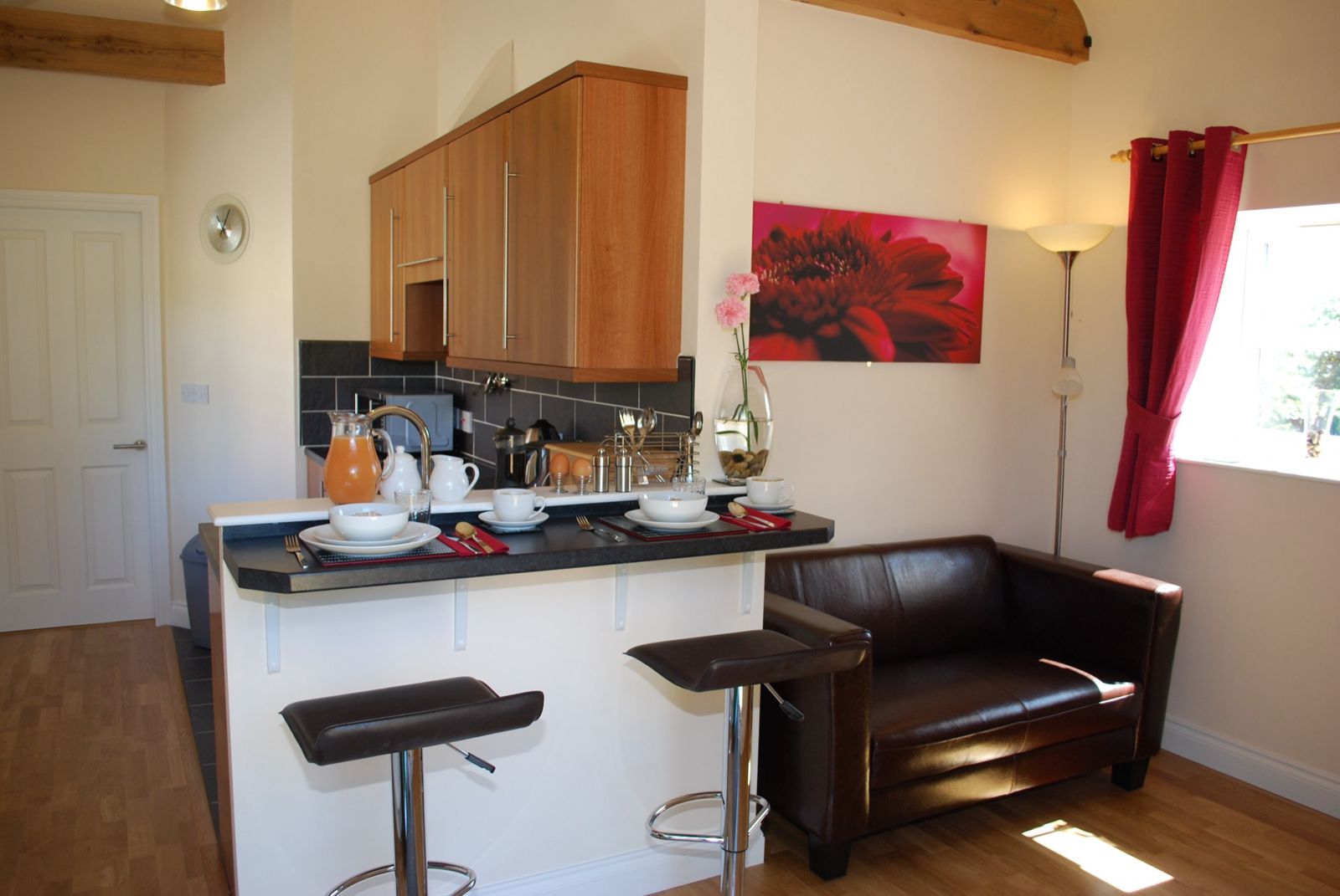 Small holiday apartment kitchen with a breakfast bar, stools and a sofa