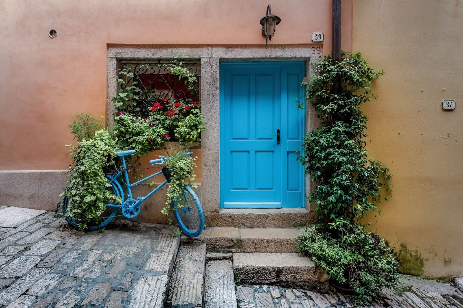 Blue painted front door and stone doorframe of an old house on a cobbled lane in Rovinj