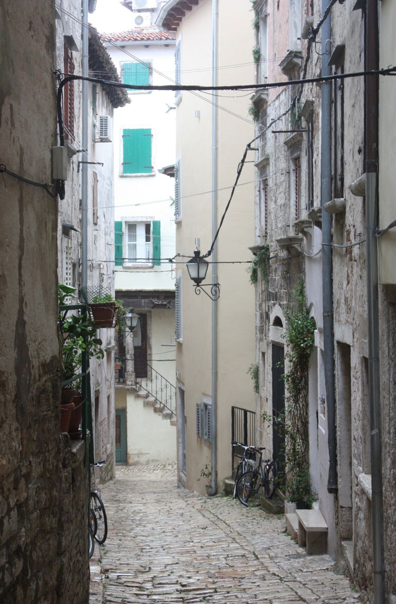 Narrow cobbled lane in the old town of Rovinj with tall stone houses on both sides