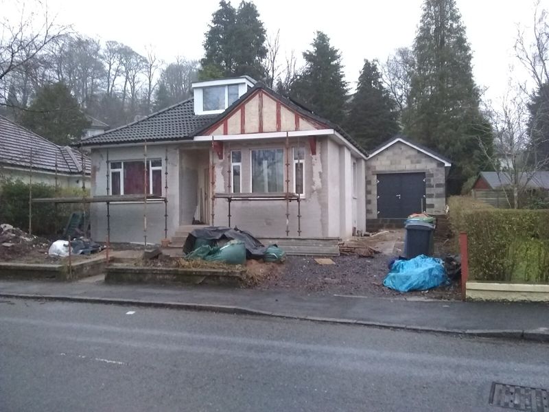 Family house under renovation with scaffolding on the facade and building materials in the front yard