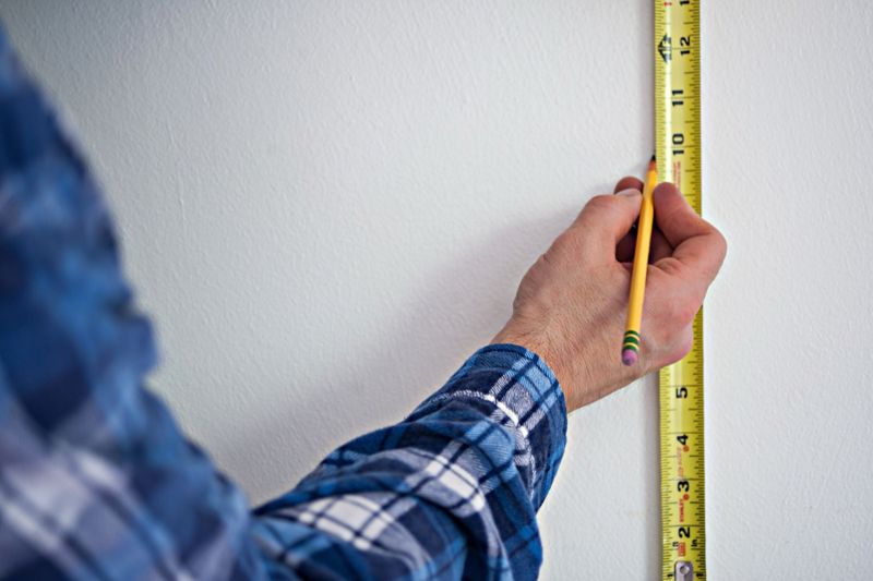 Measuring tape and pencil marking on a white wall before work starts
