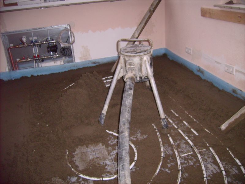 Fresh floor screed being laid over underfloor heating pipes