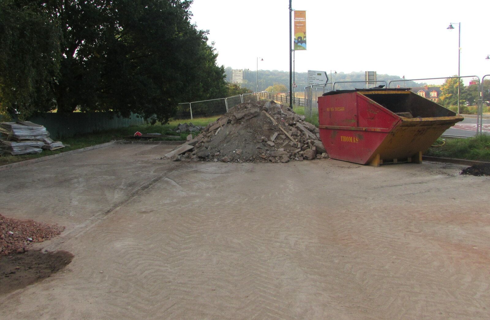 Construction site with a red skip and a heap of rubble