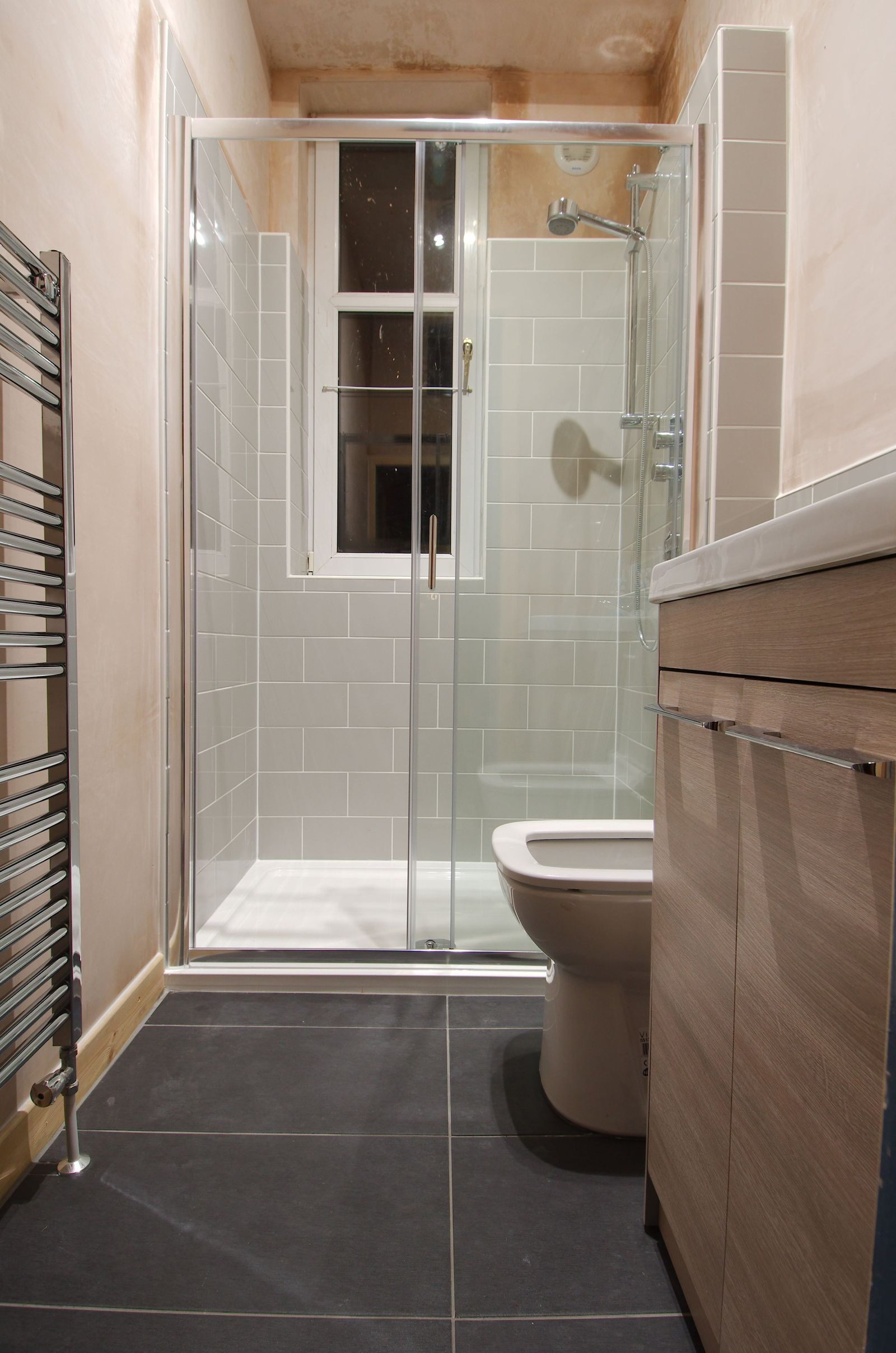 Finished shower room with light tiles, glass screen and wall-mounted fittings