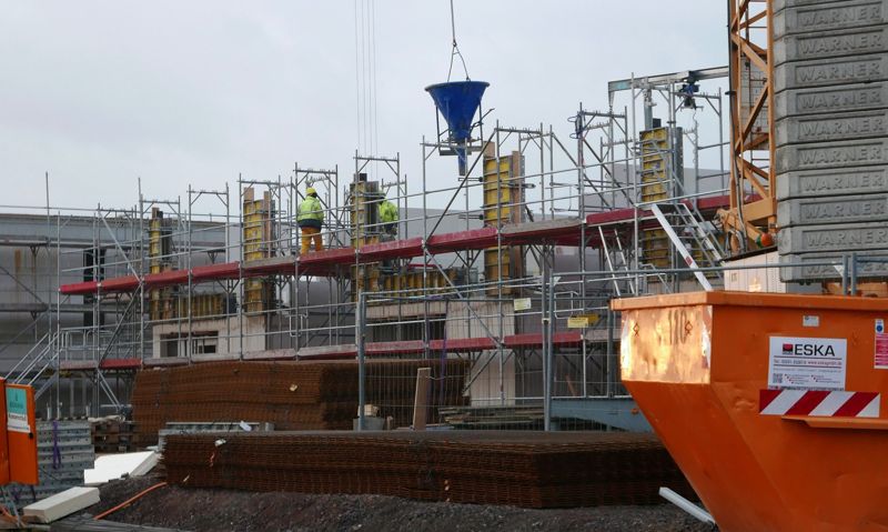 Construction site with scaffolding and a waste skip in front of the building