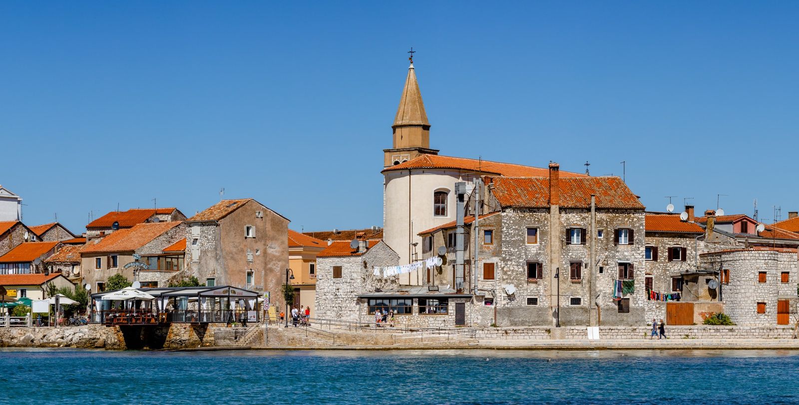 Old stone houses with shutters and tiled roofs on the seafront in Umag