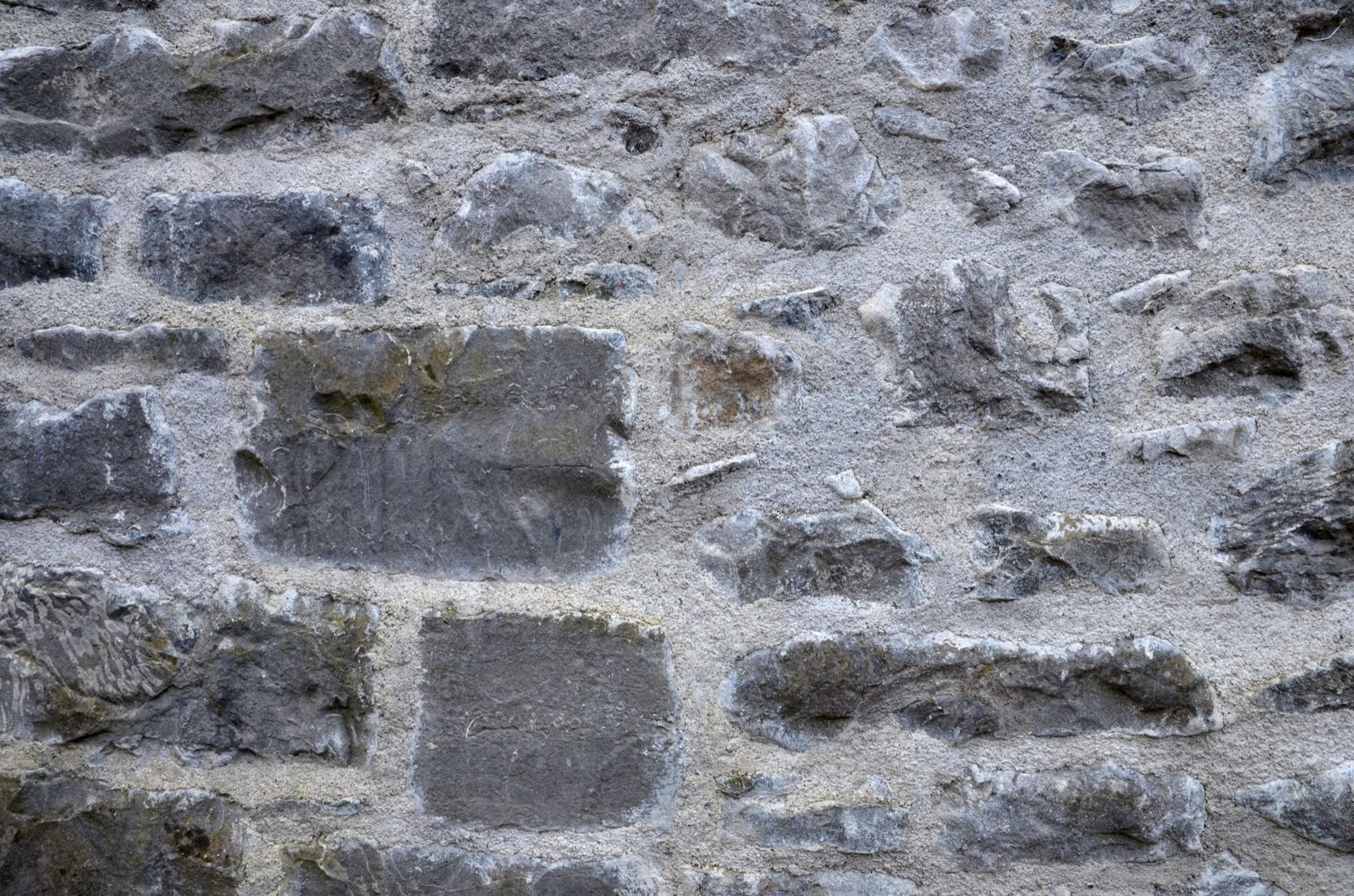 Close-up of a rubble stone wall with light lime mortar joints