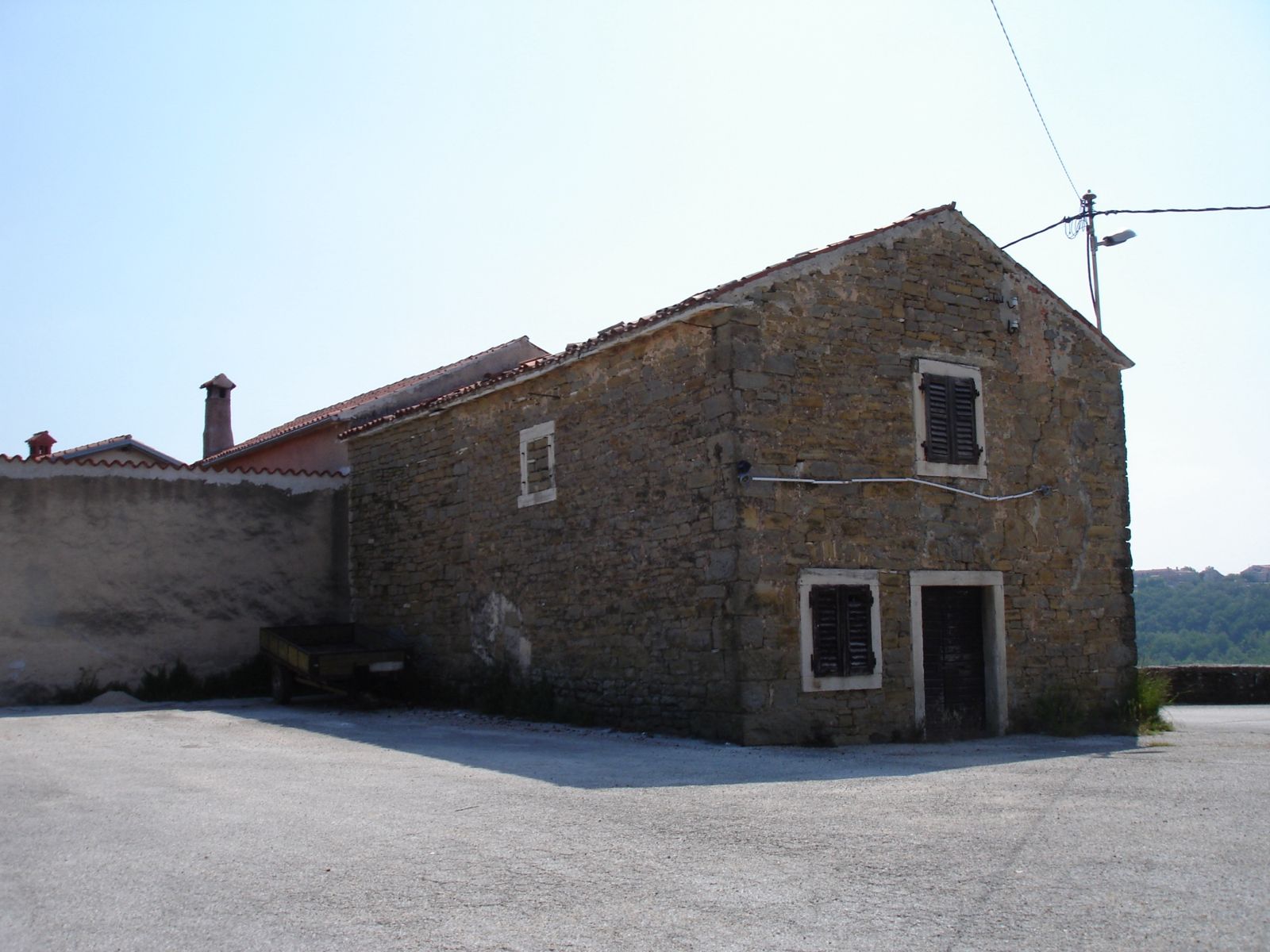 Old two-storey limestone house with small windows and a clay tile roof in the village of Momjan