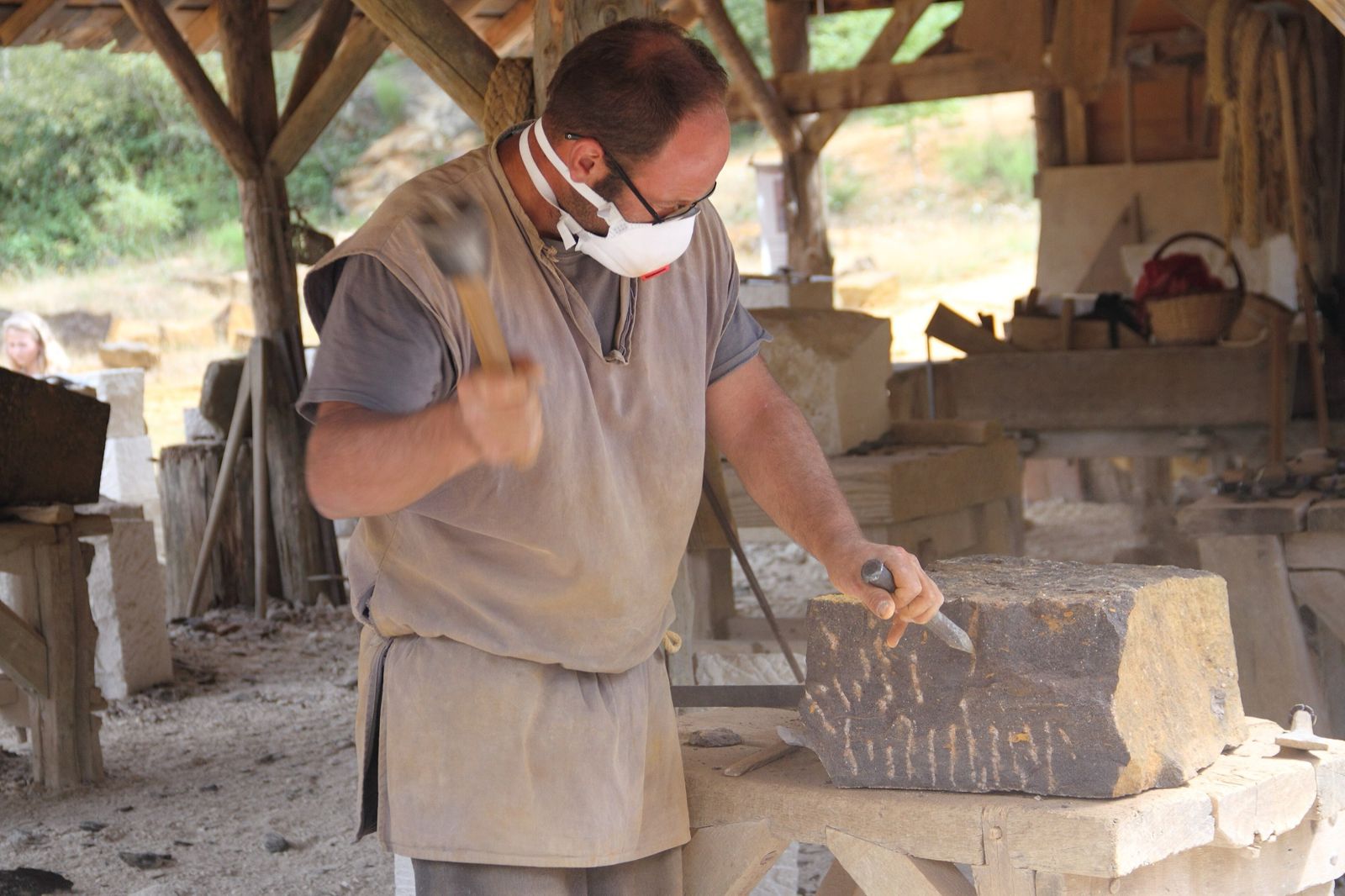 Stonemason dressing a block of stone with a hammer and chisel