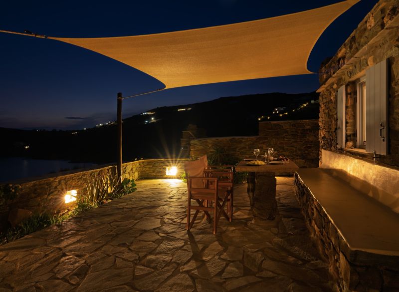 Terrace by the sea at dusk with a table set under a shade sail