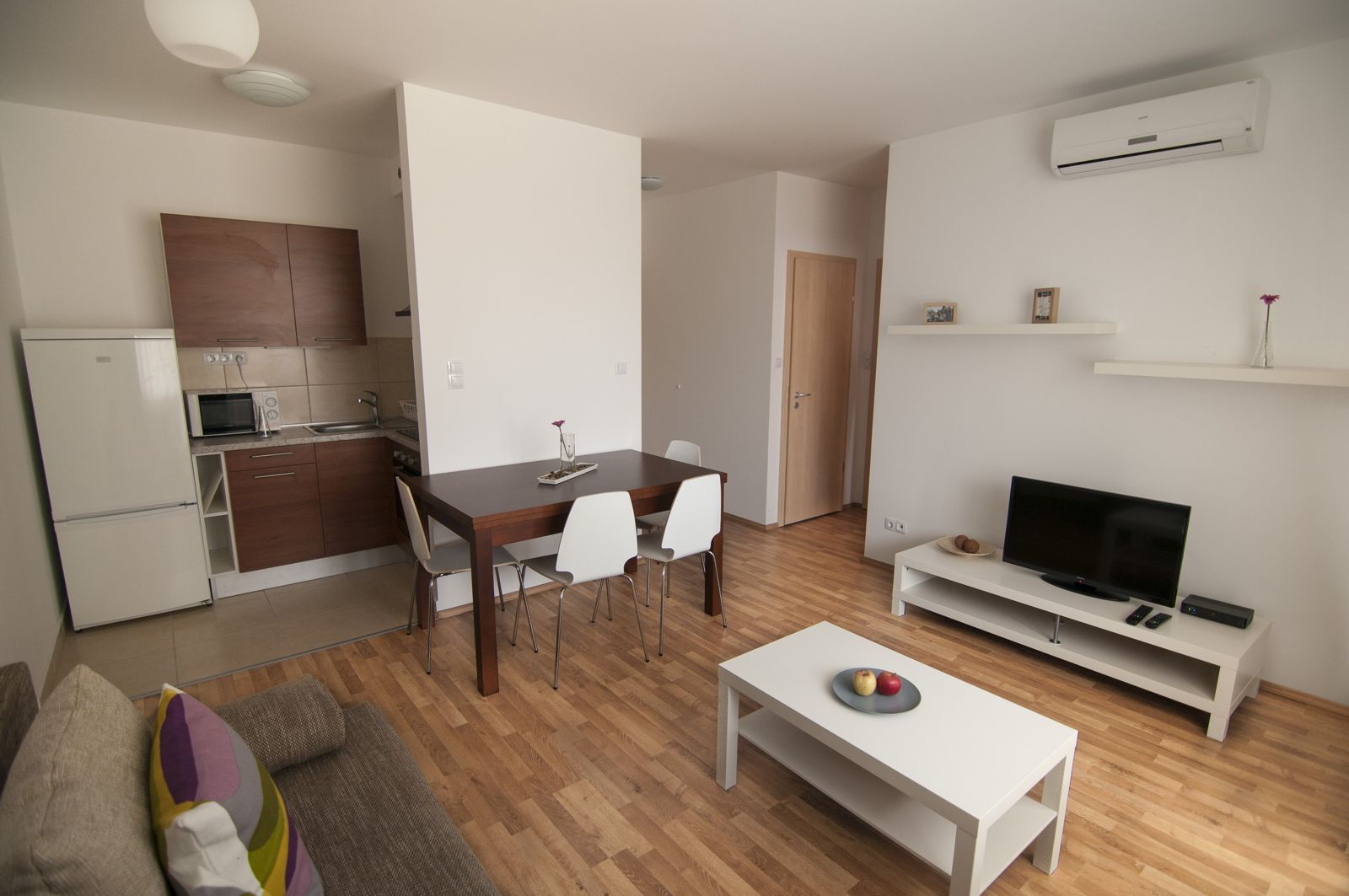 Furnished open-plan apartment with a kitchen, dining table, sofa and TV