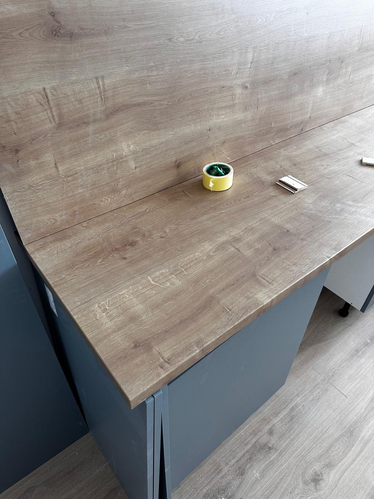 New wood-effect kitchen worktop being fitted on grey base cabinets