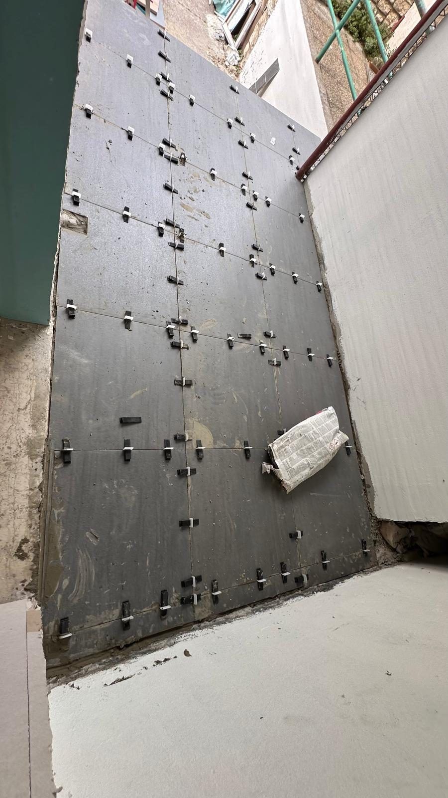 Tiler fixing light wall tiles in a room under renovation